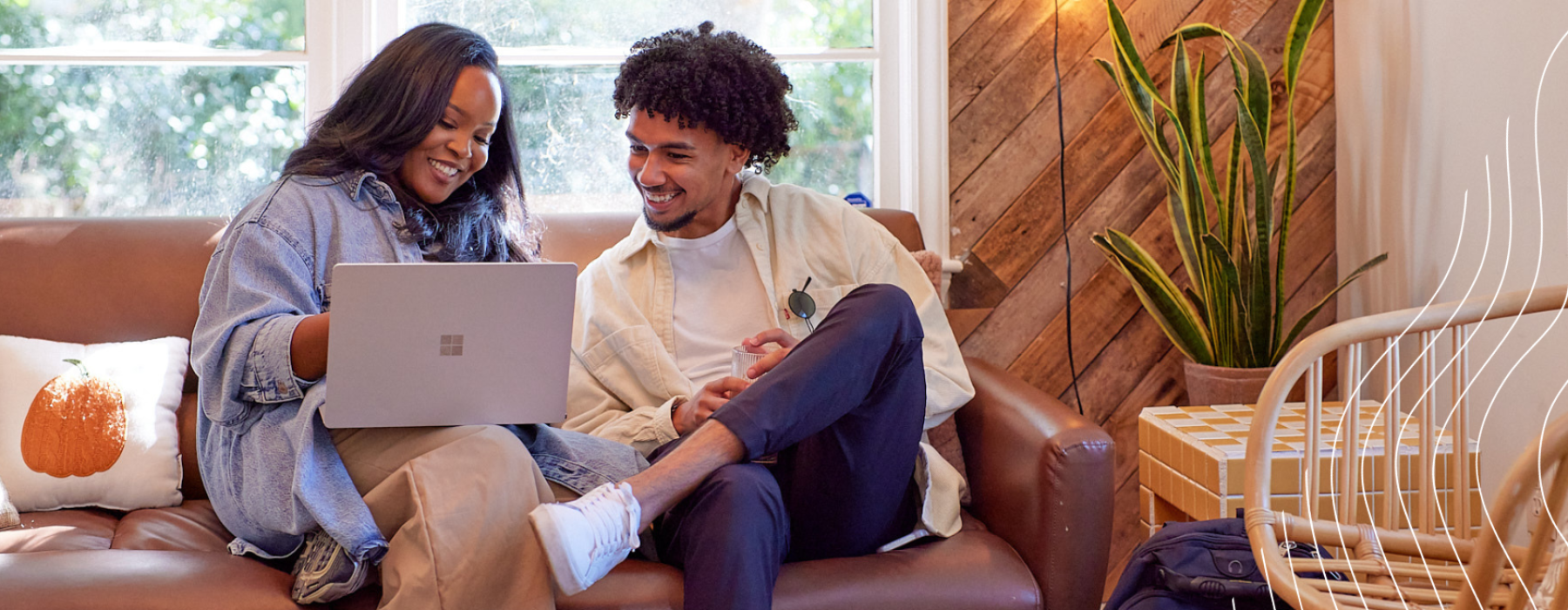 a man and a woman sitting on a couch looking at a computer